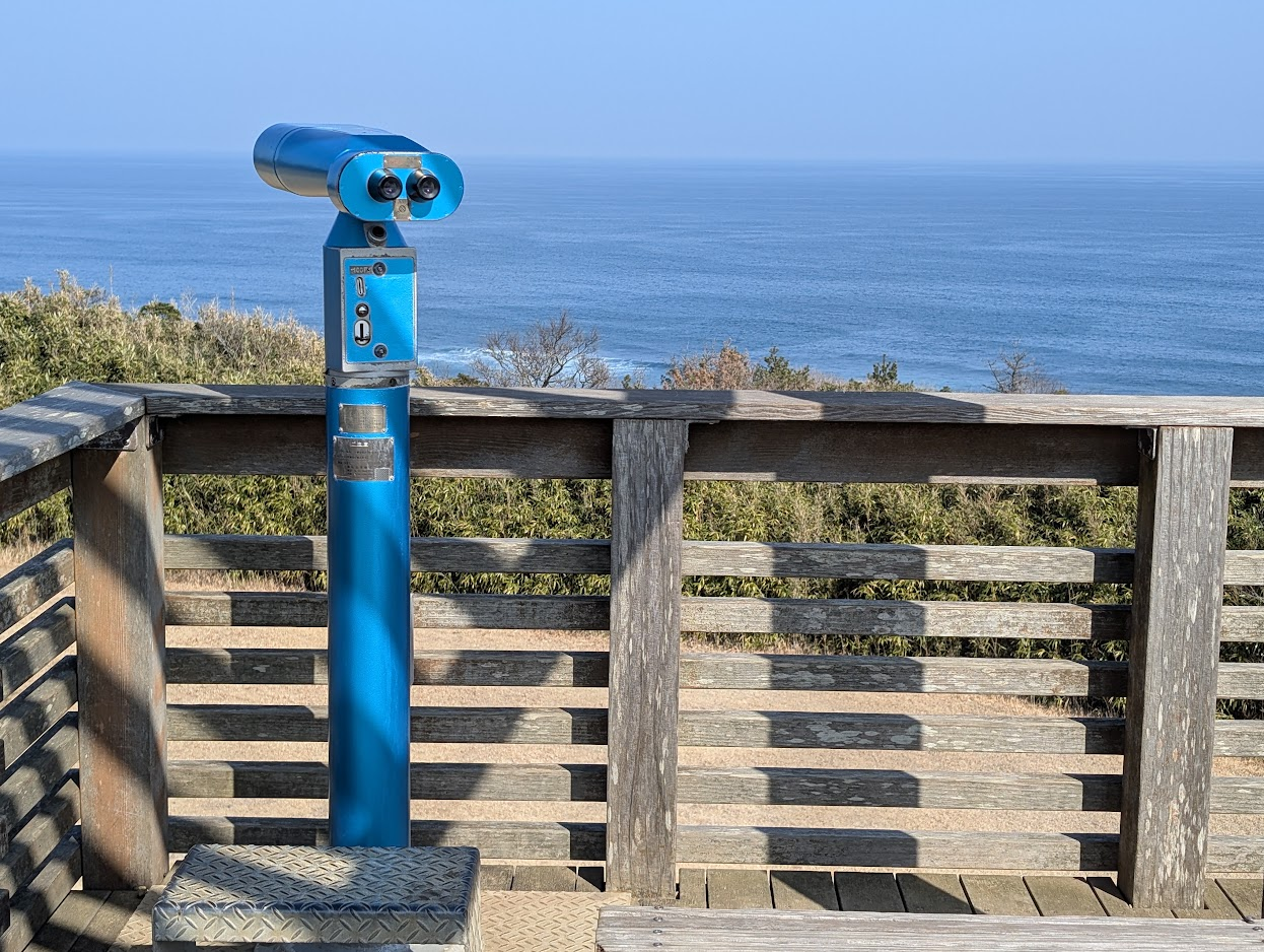 青い望遠鏡と木の柵の向こうに広がる海